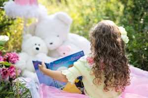 en jente som leser bok for bamsene sine