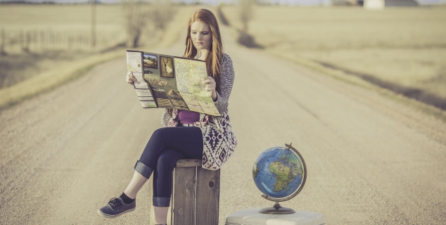 Foto av en ung dame som sitter på en koffert og ser på et kart