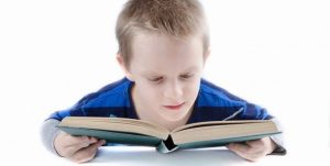 Fotografi av en gutt som leser i en bok.