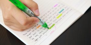 Bilde av en hånd som holder en highlighter penn og stryker over med grønn farge i boken