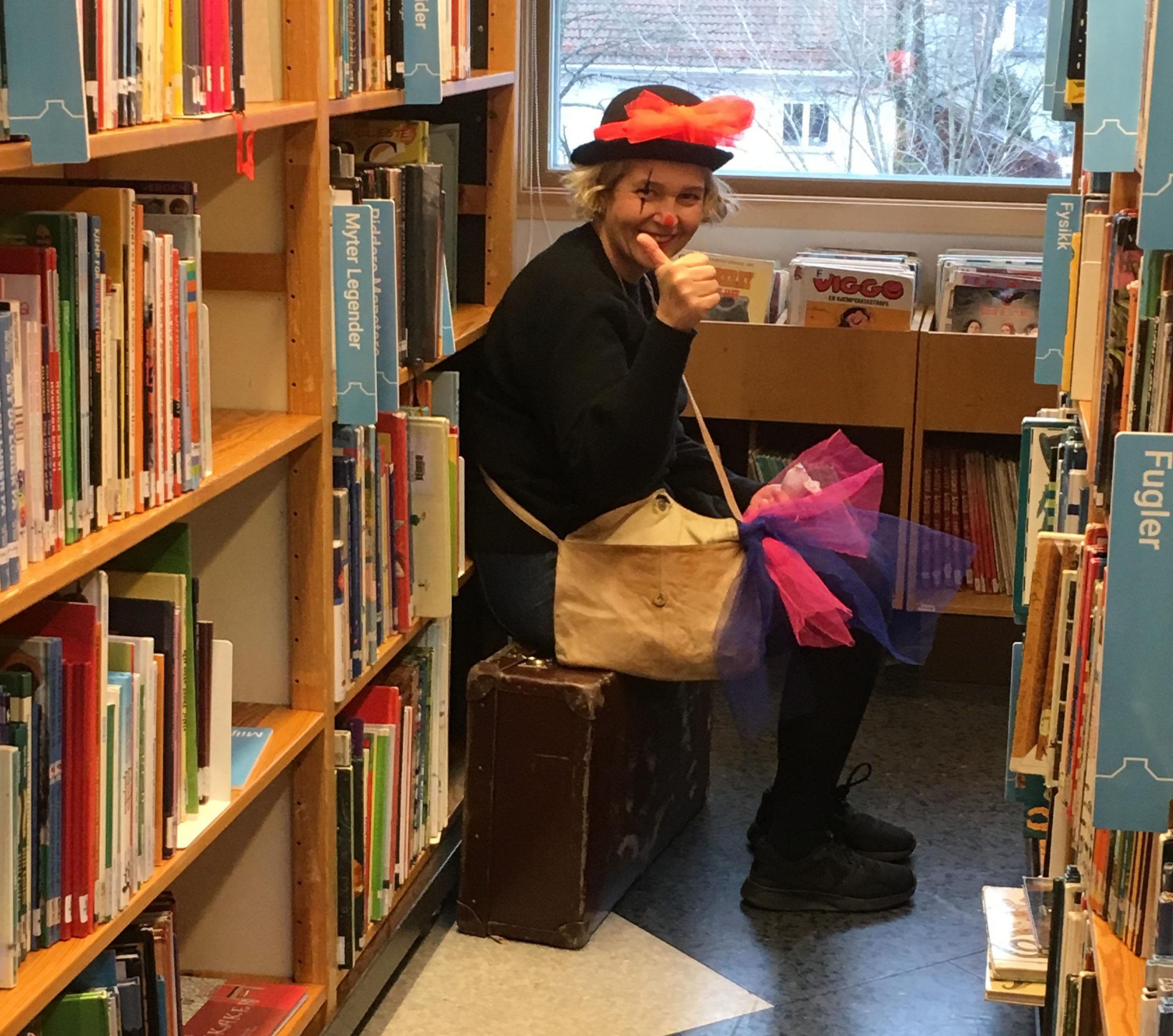 En dame med bowlerhatt mellom to bokreoler på biblioteket