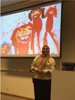 Ilham Tawfiq foran et prosjektert bilde av en barnetegning