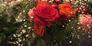 Bilde av oransje, rosa og røde roser med små hvite blomster i en bukett •