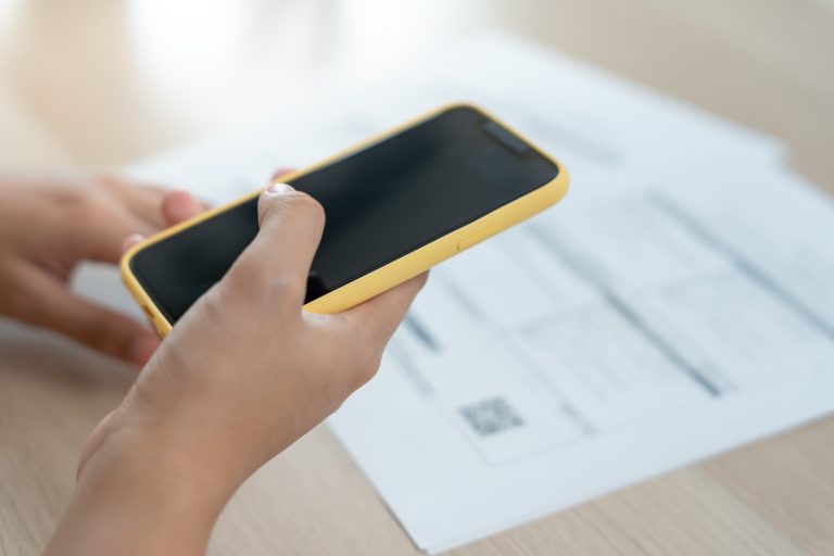 Vider en som hollder en mobil i hånden og scanner en qr kode på et papir