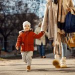 A little boy holding hands with his mother and going to the kind