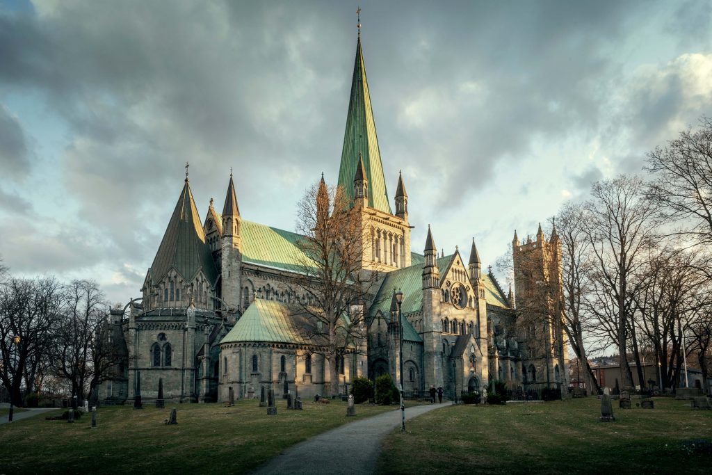 Fotografi av en stor, grå kirke med mange spir. Spirene og taker er dekket av grønn kobber. 