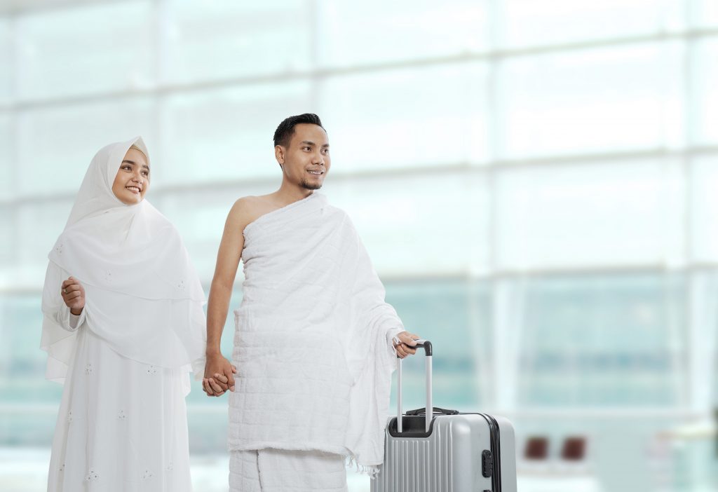 Bilde av to personer ikledd hvit kjortel på en flyplass klare for avreise til Hajj.