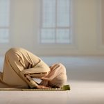 Kvinne i lang beige kjole som bøyer seg i bønn mot Mekka.