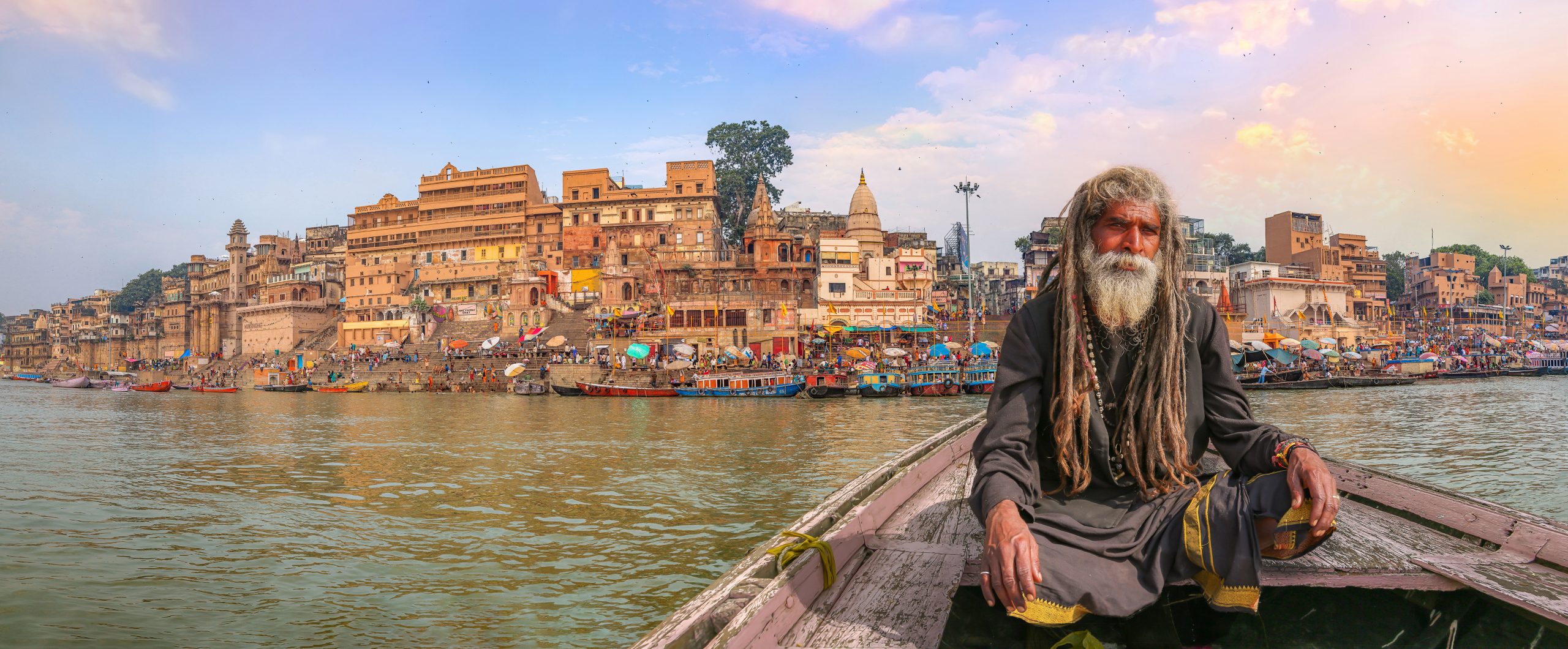 En eldre mann i en robåt på elven Ganges ved byen Varanasi i India