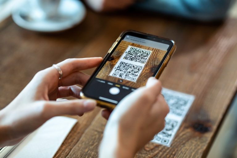 Bilde av en som tar bilde av en qr kode med mobilen sin