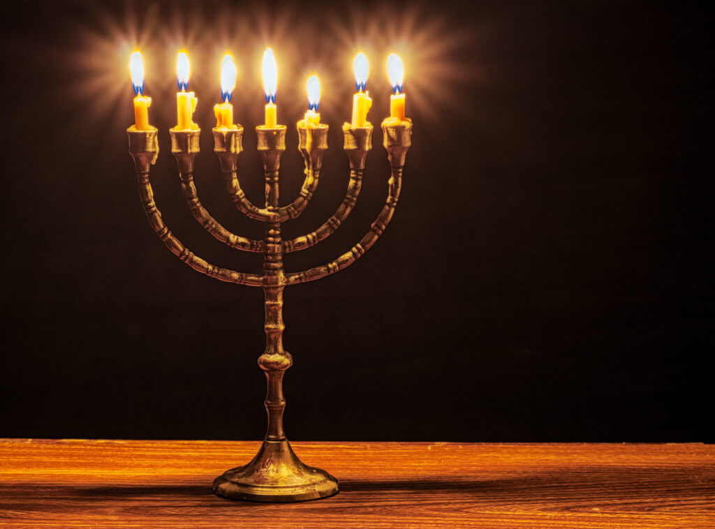En syv-armet menorah står plassert på et bord, med lysene tent i varme, gylne flammer.
