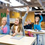 Bilde av elever som slitter i klassen. Noen av dem rekker opp hånda.