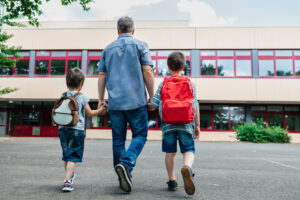 Fotografi av en mann som følger to gutter til skolen