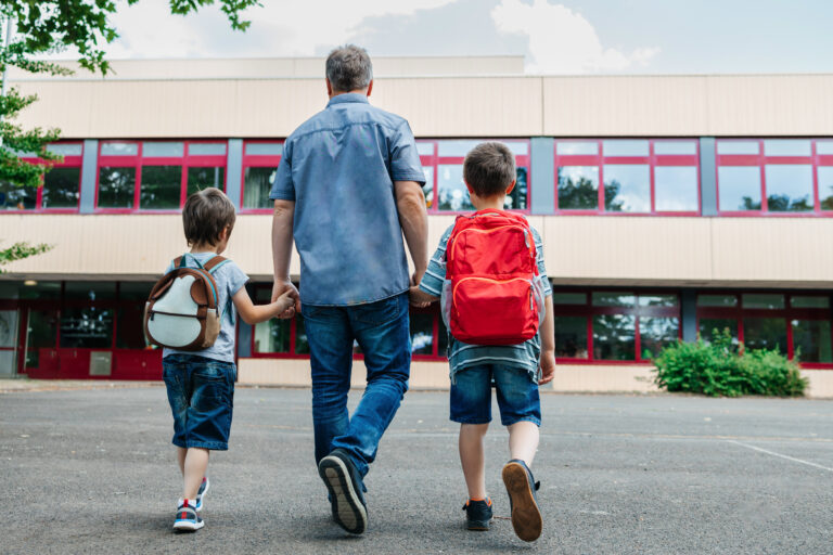 Fotografi av en mann som følger to gutter til skolen