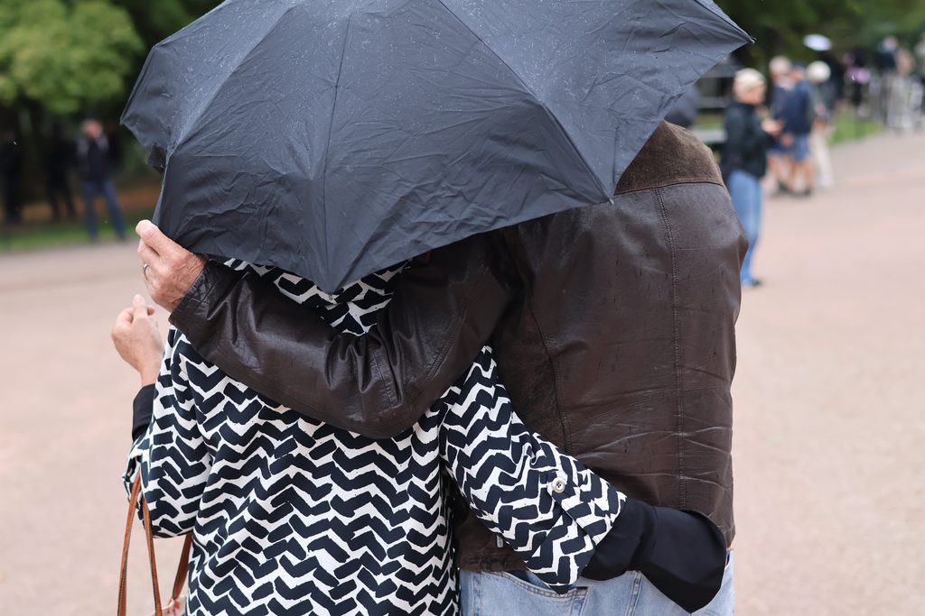 Bilde av to personer som holder rundt hverandre under en paraply