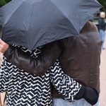 Bilde av to personer som holder rundt hverandre under en paraply