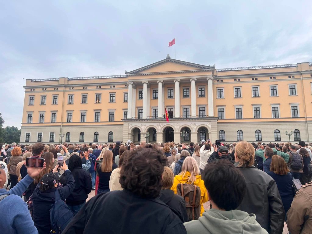 Bilde som viser mange mennesker som har samlet seg foran slottet i Oslo fredag 28.8.2026