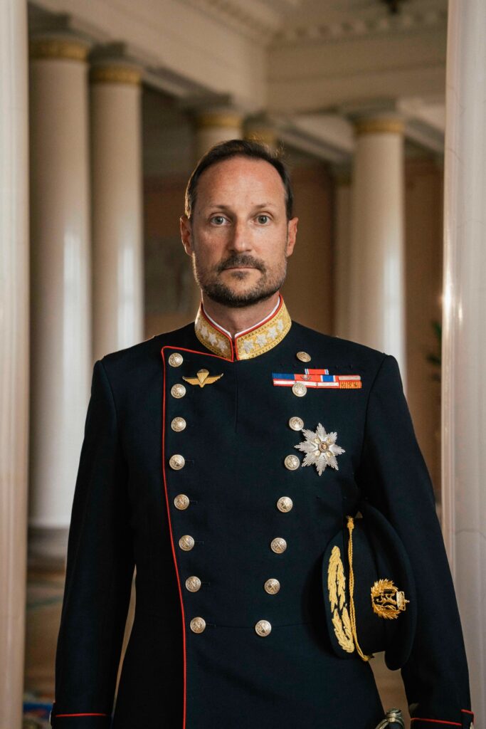 Fotografi av en mann med uniform. Noen medaljer er festet til uniformen som har sølvknapper og gullfarget krage.