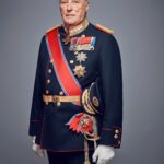 Fotofrafi av en gammel mann med uniform. På uniformen er det festet mange medaljer og han har et bånd på skrå over skulderen. Båndet er rødt hvitt og blått. Han har hvire hansker og holder et sverd i hånda.