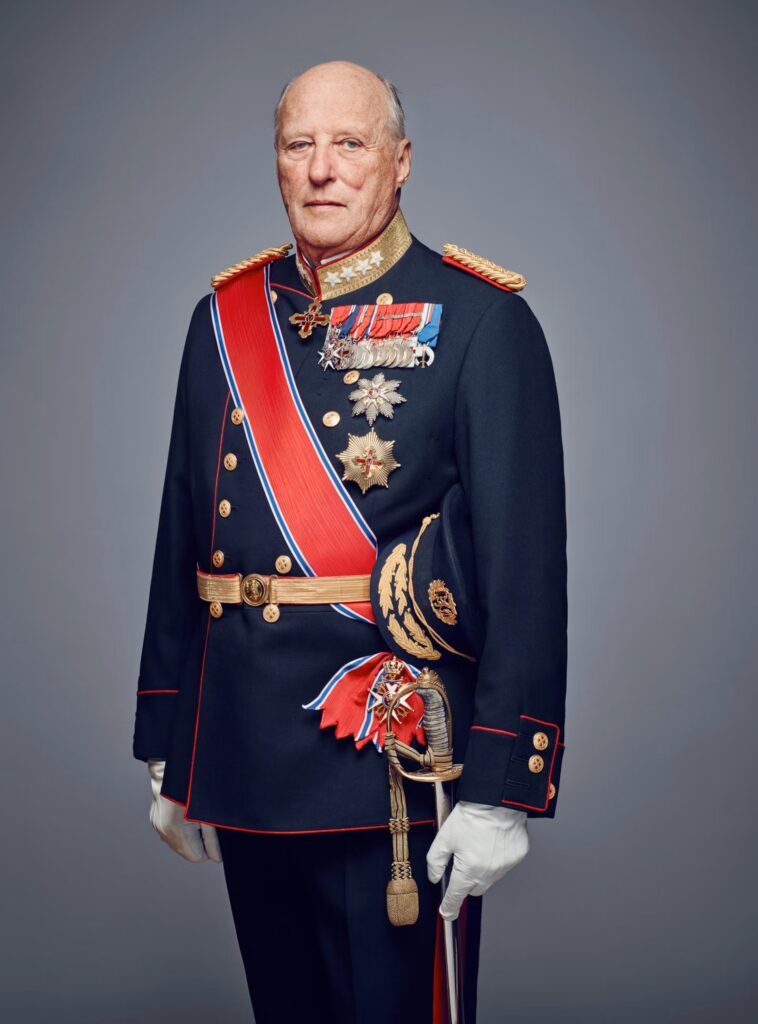 Fotofrafi av en gammel mann med uniform. På uniformen er det festet mange medaljer og han har et bånd på skrå over skulderen. Båndet er rødt hvitt og blått. Han har hvire hansker og holder et sverd i hånda.